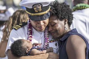 Navy Lt. Cmdr. Joseph Edwards embraces his wife and child