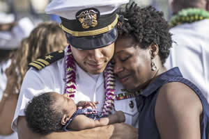 navy lt. cmdr. joseph edwards embraces his wife and child